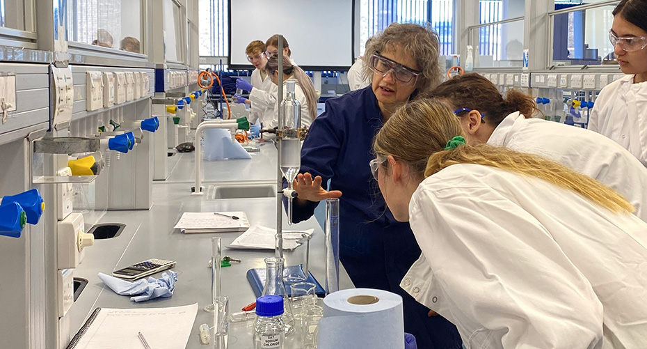 Dr Alison Hill demonstrating an experiment to some students in a lab