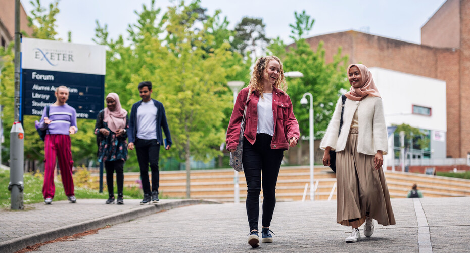 Five people walking and chatting on Streatham Campus